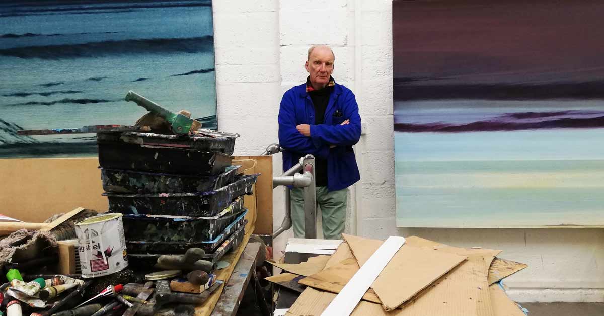Renowned Artist Jock McFadyen posing with his work in his studio.