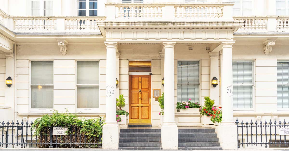 A wooden door with a brass knocker stands between two columns, flanked by windows and potted plants. Text: "PRINCES GATE 71-72" and a sign, "THE OCCUPIER OF GLASGOW HOUSE," below foliage.