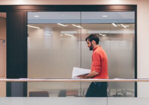 Man walking down a glass walkway in an office